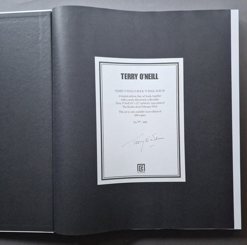 An open book showing a signed interior page with a white label reading 'TERRY O'Neill' and a signature at the bottom, photographed against a dark background.