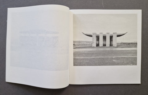 An open book, showing a black-and-white architectural photograph printed on the right page and a faintly visible page on the left.
