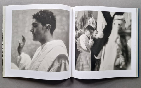 An open book showing two black-and-white printed photographs on the pages, photographed from above on a dark gray surface.