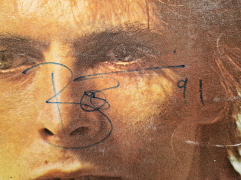 Close-up of Bowie's signature in blue ink across his portrait on the cover of Space Oddity LP record's sleeve.