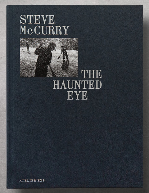 the navy book cover of The Haunted eye by Steve McCurry with a small photograph tip-on and the title and artist's name in silver
