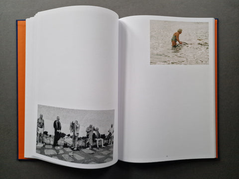 An open hardcover - a black-and-white scene on the left page and a small color photo on the right page. The book has a bright orange cover edge visible on both sides.
