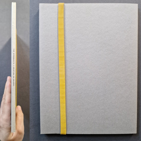 The spine and back cover with the original yellow elastic band visible of the book "The Afronauts" by Cristina De Middel