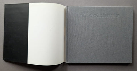 An open book with a black cover on the left, blank white pages in the center, and a textured gray cover on the right embossed with the title 'The Animals'.