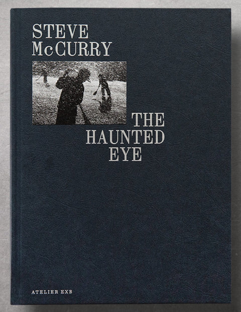 the navy book cover of The Haunted eye by Steve McCurry with a small photograph tip-on and the title and artist's name in silver