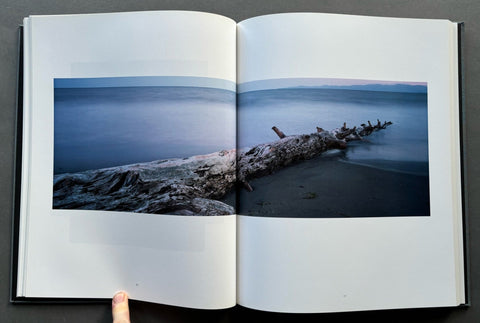 Open book showing a photograph of a beach with a log and ocean view.