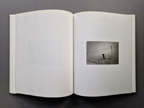 An open book spread showing a photo of a man going through a storm on the right.