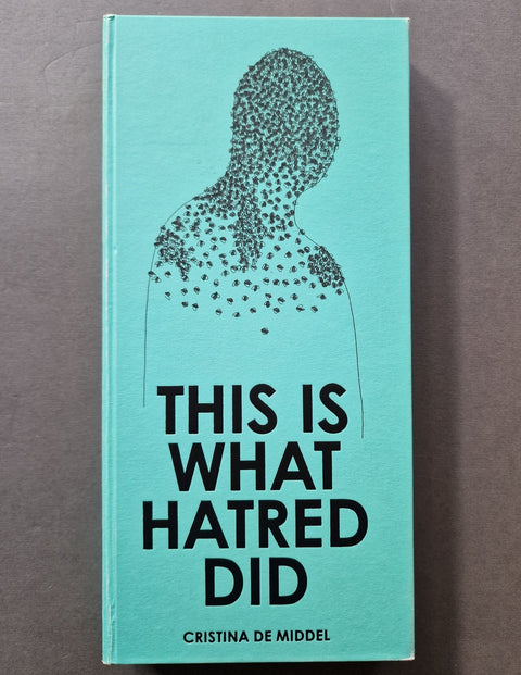 The book cover of 'This Is What Hatred Did' by Cristina De Middel, featuring a light turquoise background with a black dotted silhouette of a person and bold black text, photographed flat on a neutral gray surface.