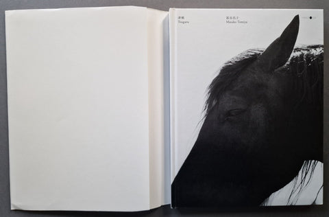 An open book, with the left page blank and the right page showing a black-and-white close-up photograph of a horse head. Small text appears at the top of the page.