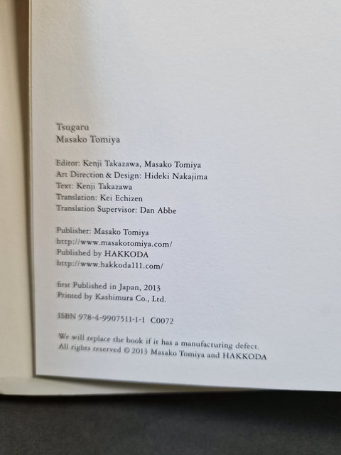 A close-up of a book's printed interior page showing publication details in black text on white paper, with a dark surface visible around the edges.