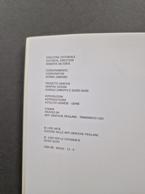 A close-up of an open book or booklet showing printed Italian copyright text on a white page, photographed against a dark gray background.