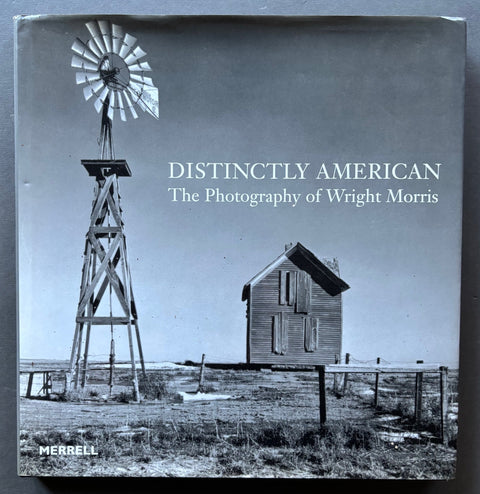 Book titled 'Distinctly American: The Photography of Wright Morris' with a cover featuring a black and white image of a rural farm building and wind turbine.