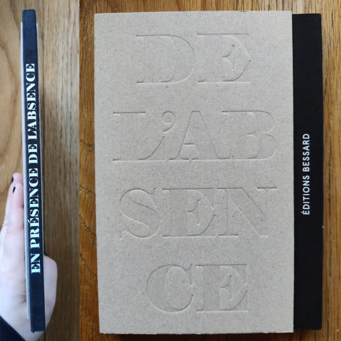 The photography book cover of En Presence de l'Absence by Jean-Marc Caimi and Valentina Piccinni. In hardcover grey with a black cloth spine.