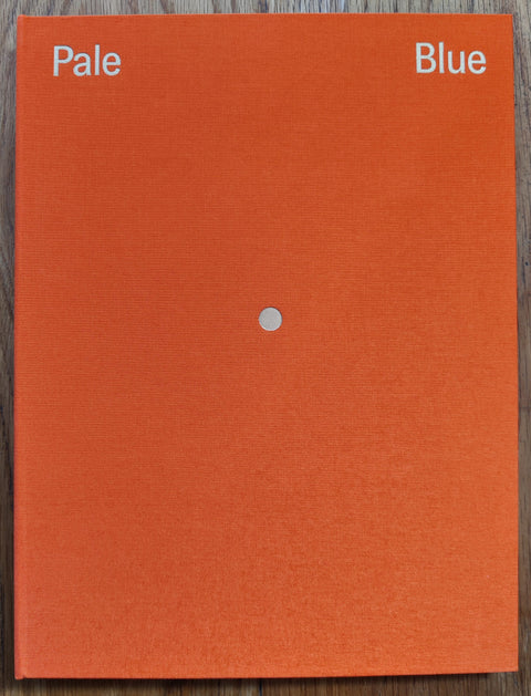 The photography book cover of Pale Blue by Albarran Cabrera. Hardback in orange with a tiny gold circle in the middle. Signed.