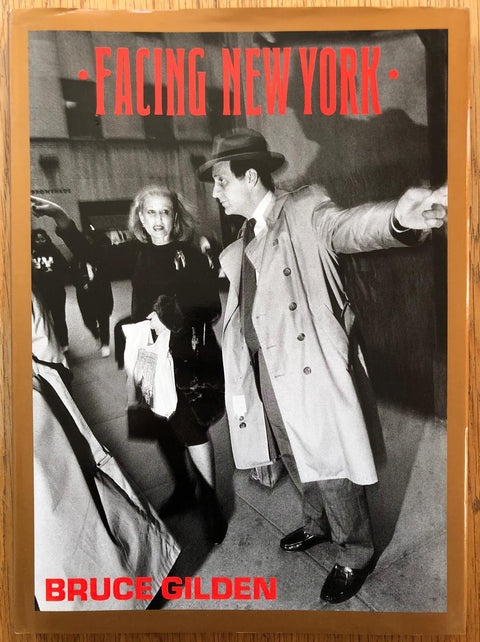 The photography book cover of Facing New York by Bruce Gilden. Hardback in b&w with brown border and red text.