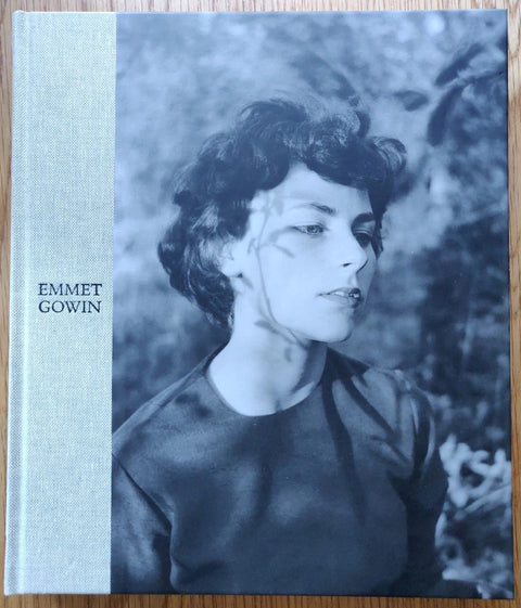 The photography book cover of A Life in Photography by Emmet Gowin. Hardback in blue/grey with photo of a woman outdoors on the cover.