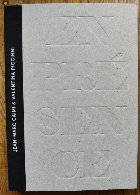 The photography book cover of En Presence de l'Absence by Jean-Marc Caimi and Valentina Piccinni. In hardcover grey with a black cloth spine.