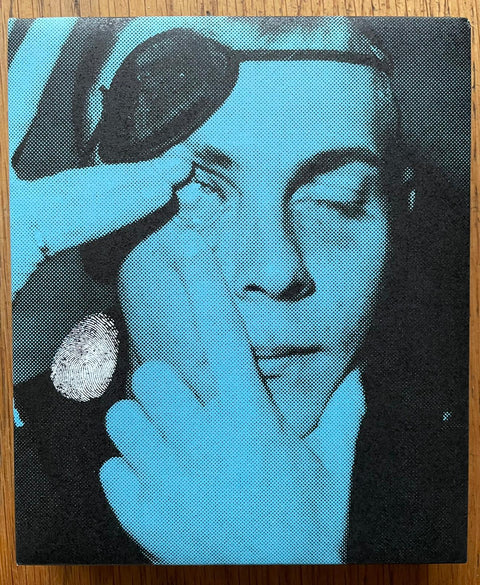 The photography book cover of Fingerprint by Jim Goldberg. Hardback box set in blue with image of a man holding his eye open.