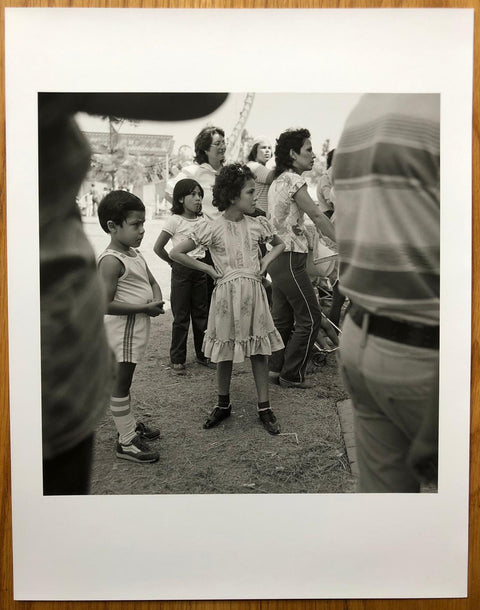 The print for Angel City West by Mark Steinmetz. B&W print of people at a fairground. Hardback yellow book, signed.