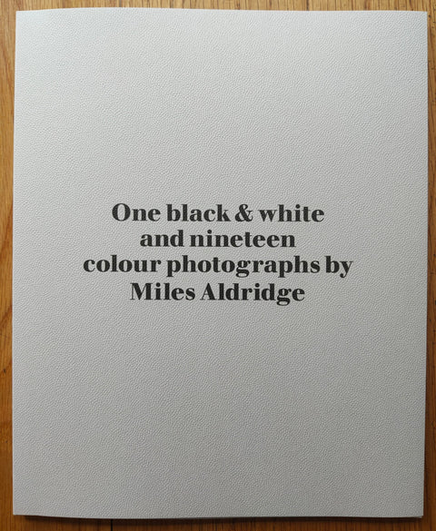 The photography book cover of One black and white and nineteen colour photographs by Miles Aldridge. Paperback in white with black title centred. Signed.