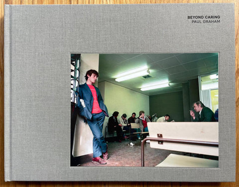 The photobook cover of Beyond Caring by Paul Graham. Hardback in grey with image of a man leaning against a wall. Signed.