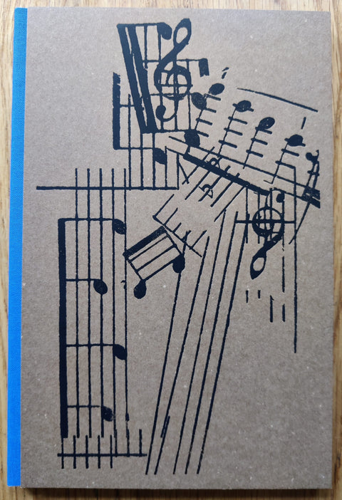The photography book cover of Estudio Elemental del Levante by Ricardo Cases. Hardback with blue binding. Brown cover has musical notes on it.