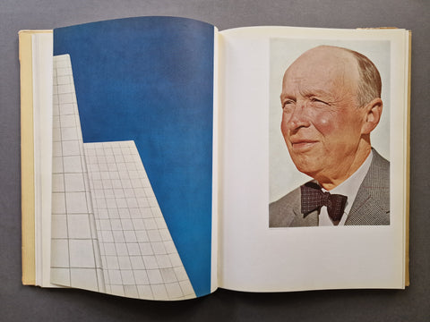 An open book spread showing an almost full bleed photo of a cityskape on the left and a portrait of a men at the top of the right page.