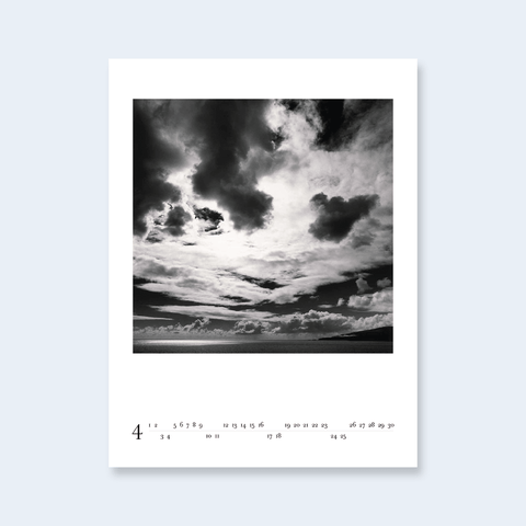 A minimalist calendar page featuring a dramatic cloudy sky photograph.