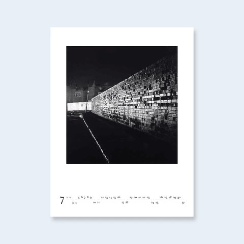 A minimalist calendar page featuring a photograph of a brick wall at night.