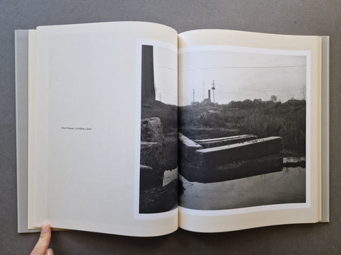 An open hardcover book, showing a black-and-white landscape photograph spread across the two pages.