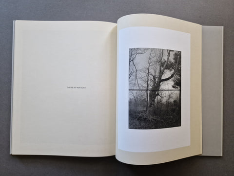 An open book , showing a black-and-white photograph of leafless tree