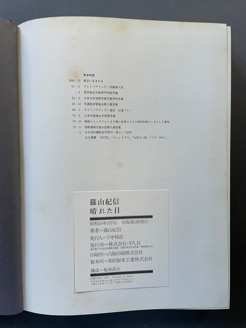 An open book or booklet showing an interior page with Japanese text and a white label card near the bottom, photographed against a dark background.