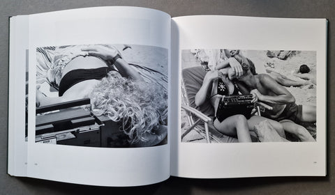 An open book, showing two black-and-white photographic prints on white pages. The left page features a high-contrast photo of a person lying down with curly hair near a beach chair.