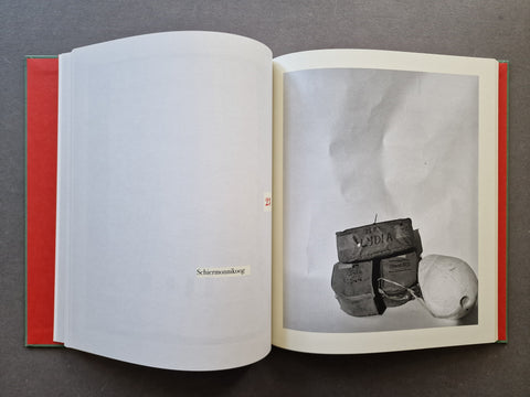 An open book where the right page shows a black-and-white still life photograph of stacked boxes and a round object.
