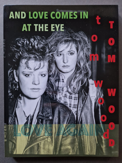 Tom Wood book cover for 'And Love Comes In At The Eye', featuring a black and white photo of two women with red and green text accents.