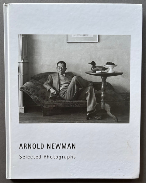 Book titled 'Arnold Newman: Selected Photographs' with a white cover featuring a photograph of a man sitting on a chaise longue.