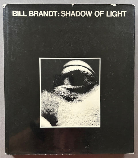 Book titled 'Shadow of Light' by Bill Brandt with a black cover and the black and white image of a person's eye.