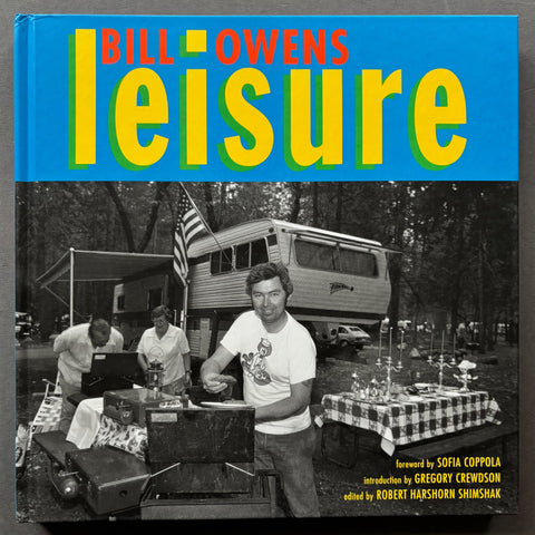 Book titled 'Leisure' by Bill Owens with a cover featuring the image of a man adding meat to a barbecue in front of a caravan.