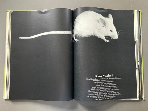 An open book spread showing a black-and-white photograph of a mouse on the left page and a poem titled 'Diana Macleod' with small white text on the right page, photographed from above on a gray surface.