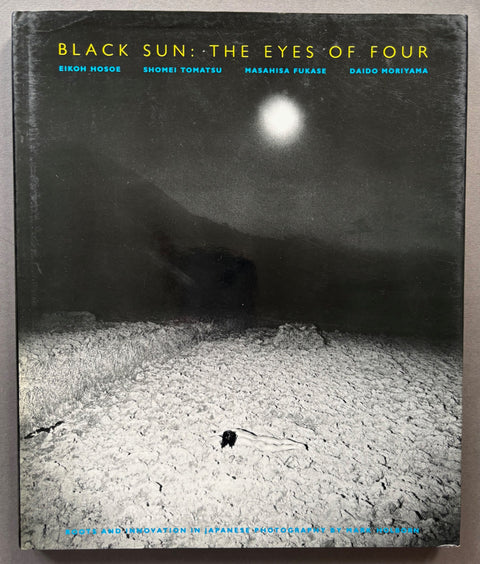 Book titled 'Black Sun: The Eyes of Four' by Eikoh Hosoe, Shomei Tomatsu, Masahisa Fukase and Daido Moriyama with a black and white cover featuring the image of a naked person lying face down on the ground.