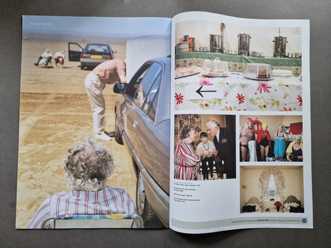 An open magazine laid flat on a dark surface, showing two spread pages filled with photographs and text. The left page features a large outdoor scene with a person beside a car, and the right page contains several smaller photos including a table setting, people, and an interior scene.