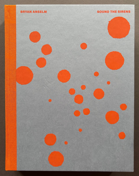 Book titled 'Sound the Sirens' by Bryan Anselm with a grey cover covered in orange spots.