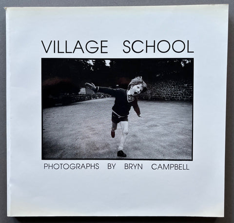 Book titled 'Village School' by Bryn Campbell with a white cover featuring the image of a boy in school uniform running with his arms outstretched.