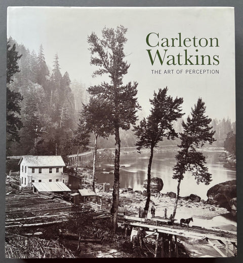 Book titled 'The Art of Perception' by Carleton Watkins with a cover featuring the image of an American landscape including a wooden built house and a bridge in amongst tall trees.