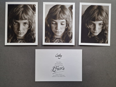 Three black-and-white portrait photographs of a young girl (Kate Bush) are arranged above a signed card of authenticity on a dark gray background.