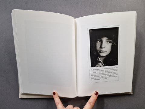 An open book, showing blank white pages on the left and a black-and-white portrait page with text on the right, set against a dark gray background.
