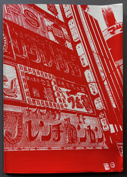 Book titled 'Momoe' by Daido Moriyama with a red and white cover with the image of a building in Japan.