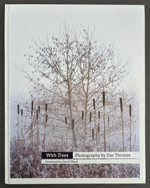 Book titled 'With Trees: Photography by Dav Thomas' with a white cover featuring the image of a tree and surrounding plants covered in frost.