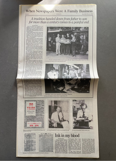 A vintage newspaper page laid flat on a dark gray surface, featuring multiple black-and-white photographs, columns of text, and a prominent headline reading 'When Newspapers Were A Family Business.'.