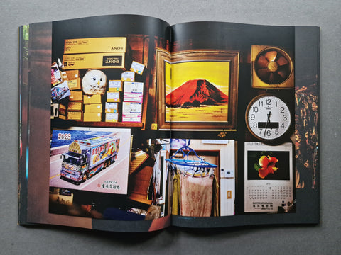 An open book, showing a collage of photographs and printed images on glossy pages, photographed from above on a dark gray surface.